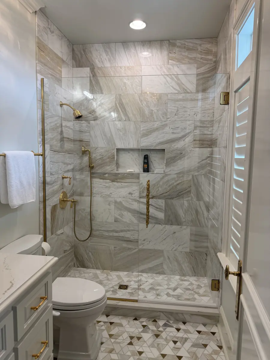 Walk-in shower with marble-look tile and brushed gold fixtures